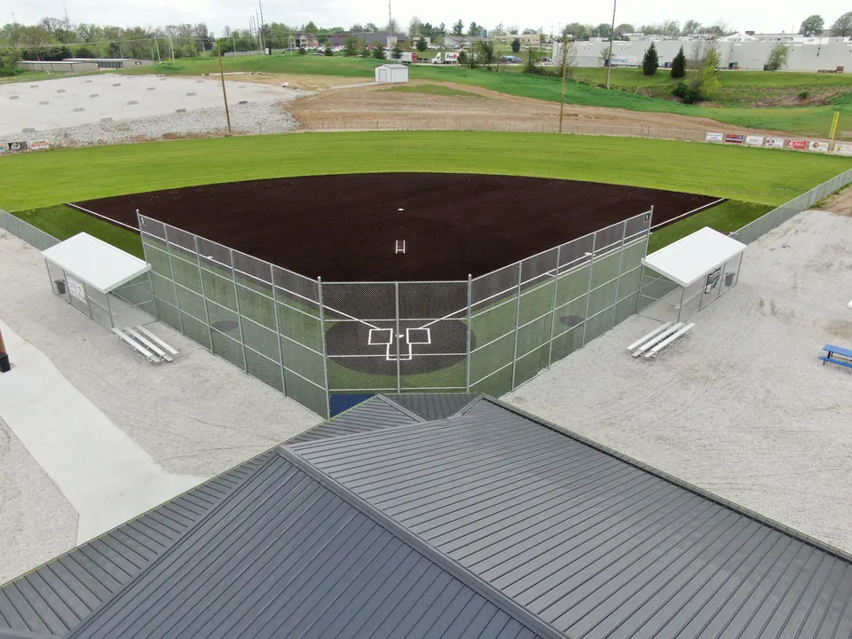 Softball field backstop with chain link fencing and covered dugouts